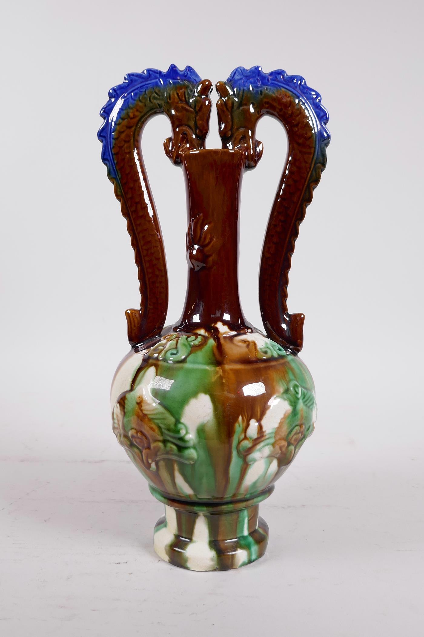 A Chinese Sancai glazed pottery vase with a slender neck and two handles in the form of dragons,