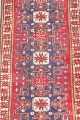 A vintage fine woven red ground Turkish rug with a blue starburst design, woven on wool, 42" x 76"