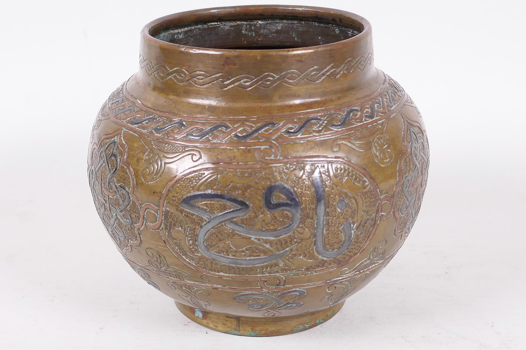 An antique Islamic brass pot decorated with inlaid copper and wire on an engraved background with - Image 2 of 4