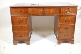 A mahogany pedestal desk with a tooled inset top, hidden keyboard drawer/slide, drawers and a