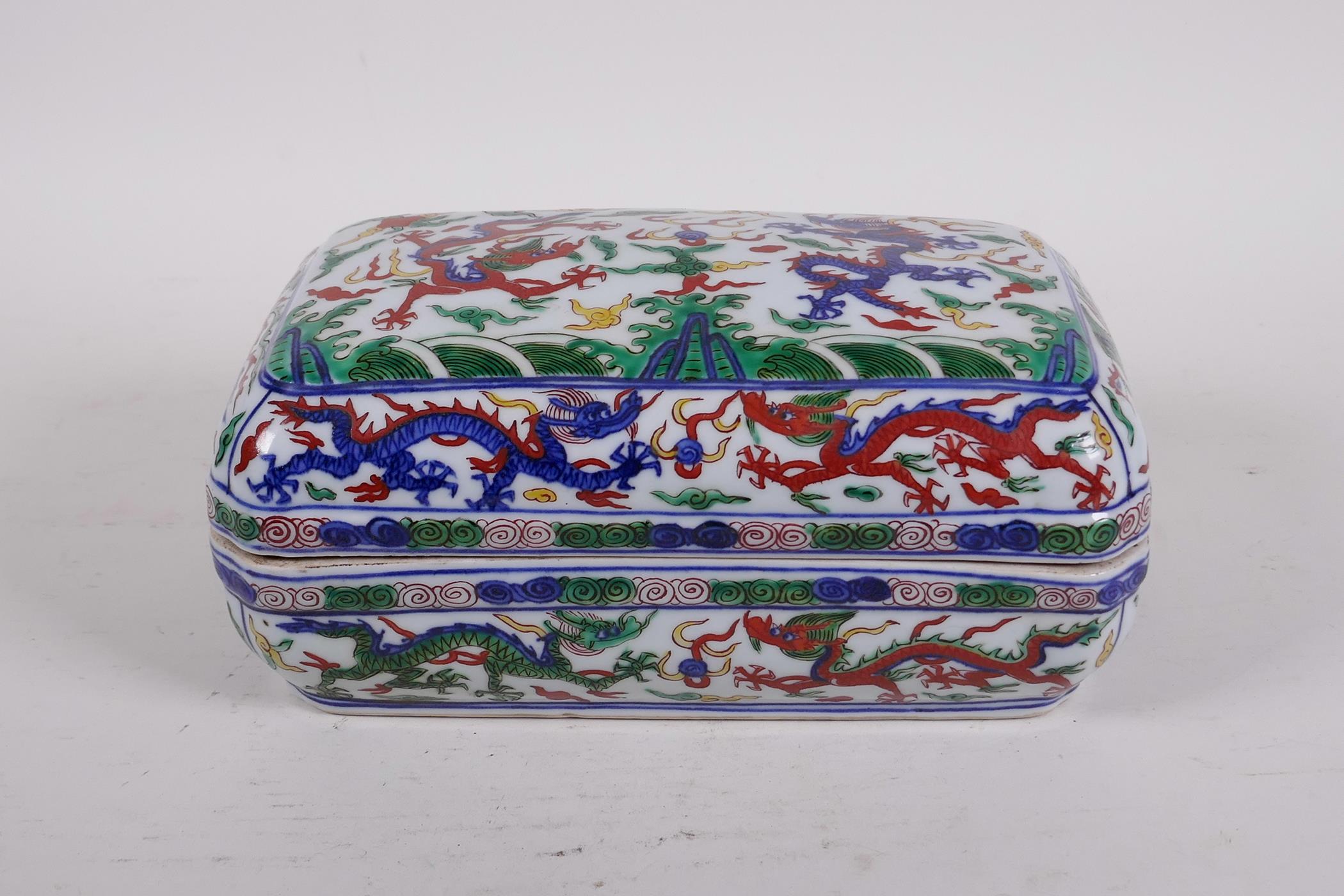 A Chinese wucai porcelain box and cover decorated with dragons and phoenix chasing the flaming