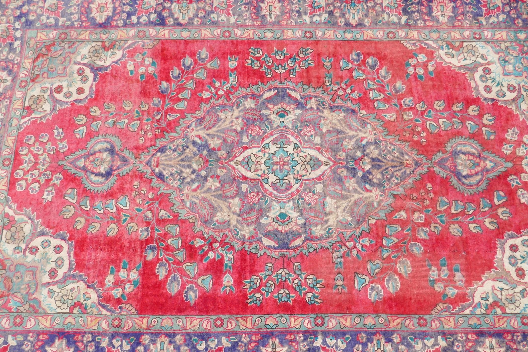 A vintage Iranian carpet from the Tabriz region, with a floral medallion design on a red field