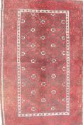 A Middle Eastern red ground wool rug with a repeating diamond pattern design, 34" x 51"