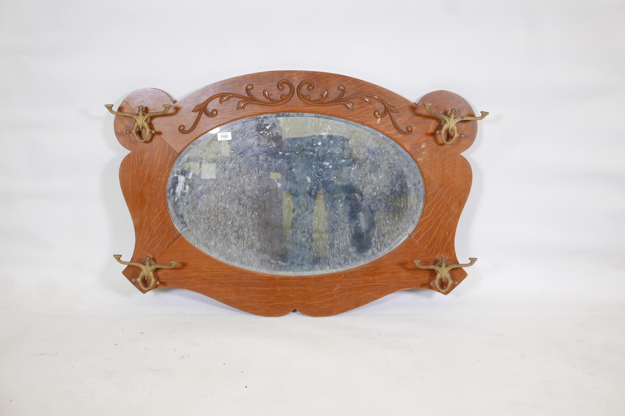 An American oak wall mirror with moulded decoration, fitted with four coat hooks, late C19th/early