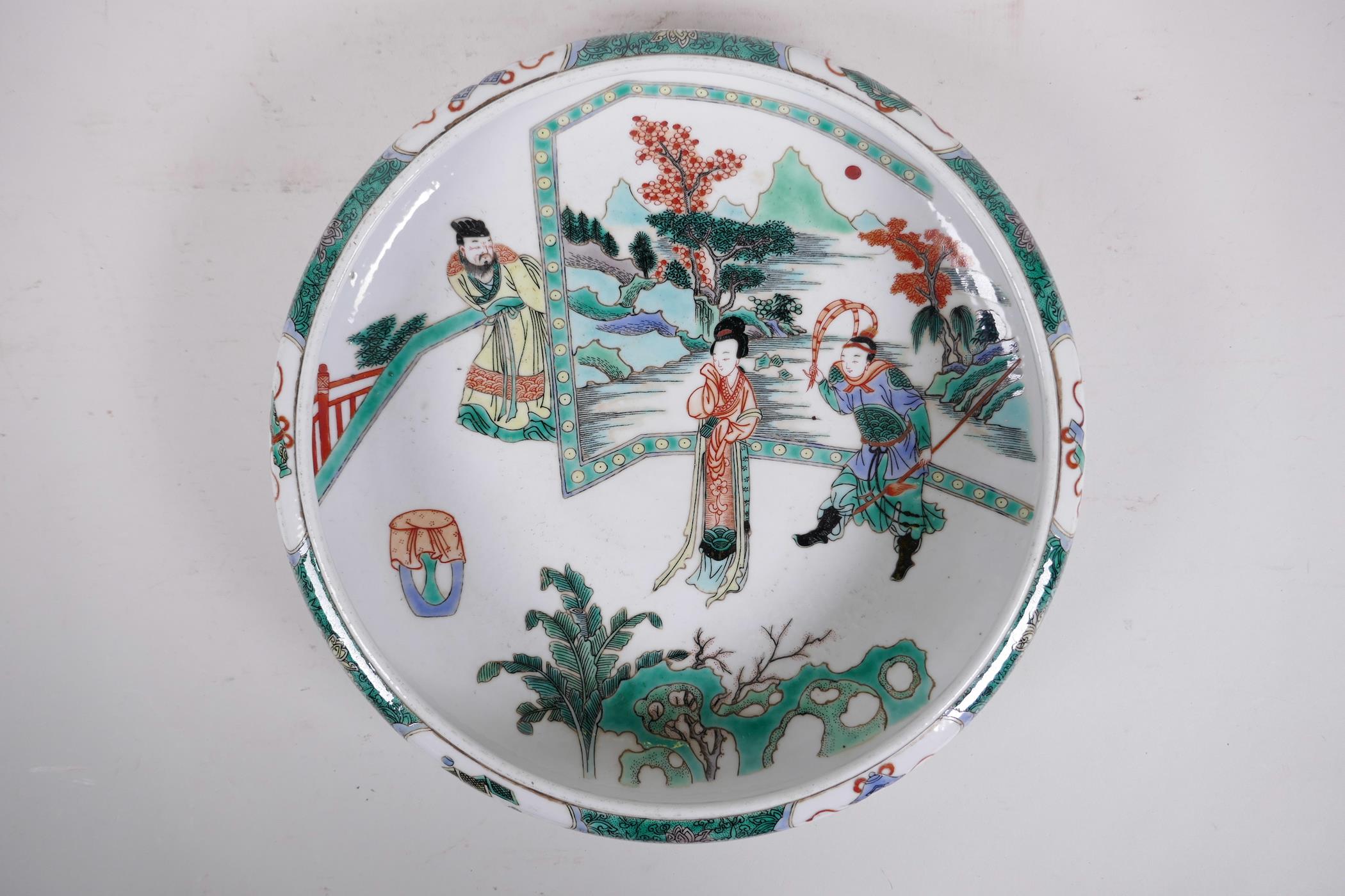 A Chinese famille verte porcelain dish with a rolled rim, decorated with figures standing in front