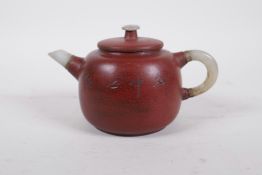 A Chinese Yixing teapot with a grey jade spout, handle and mount, the sides decorated with character