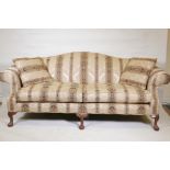 A camel back settee with scroll arms, raised on carved cabriole supports with ball and claw feet,