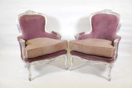 A pair of Continental Louis XV style armchairs with silver leafed decoration and distressed silk