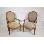 A pair of walnut spoonback open armchairs with carved and shaped arms, raised on cabriole supports