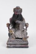 A Chinese carved, patinated and giltwood figure of an emperor seated on a throne, with a human