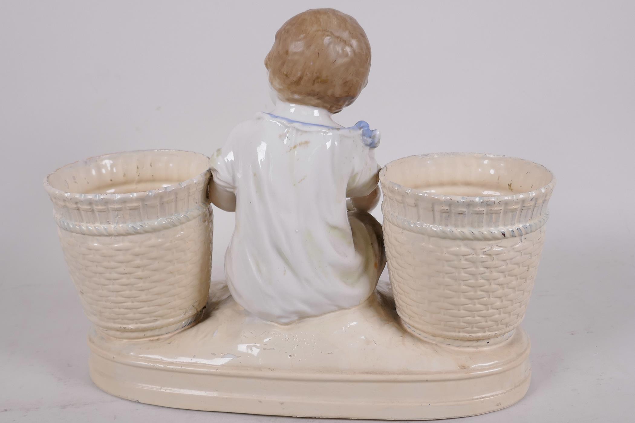A decorative porcelain planter in the form of a young girl seated between two large baskets, 11½" - Image 3 of 3