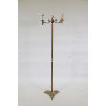 A brass two branch floor lamp of classical form, with fluted column, triform base and paw feet,