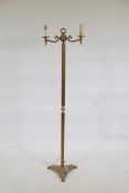 A brass two branch floor lamp of classical form, with fluted column, triform base and paw feet,