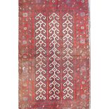 A Middle Eastern full pile red ground wool rug with a three panel geometric design, 34" x 56"