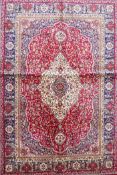 A red ground full pile Kashmir rug with a floral medallion design, 46" x 68"