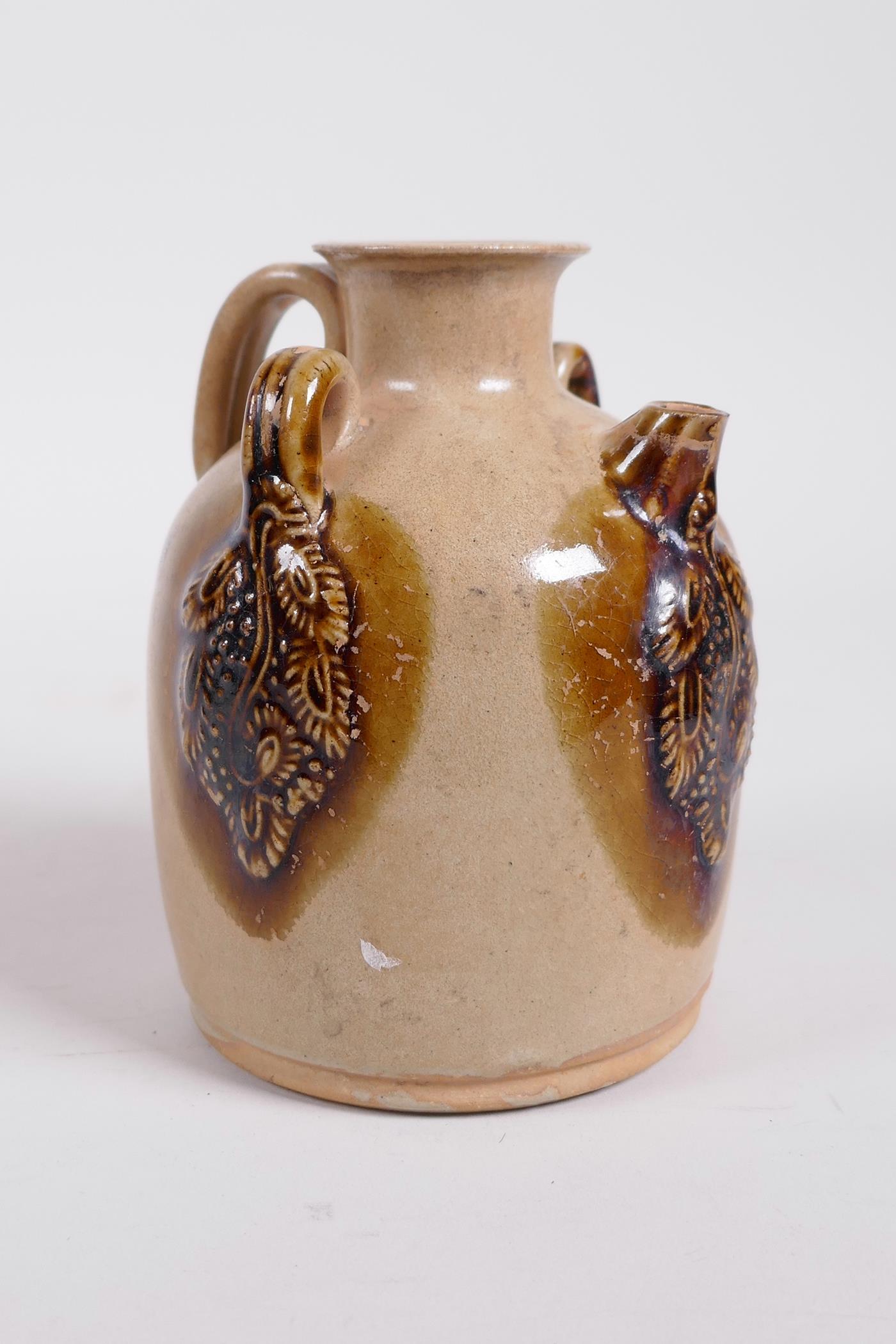 A Chinese ochre ground Changsha kiln pottery wine pourer with raised and glazed vine decoration