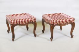 A pair of walnut footstools raised on cabriole supports with scroll ends, 17" x 17" x 14"