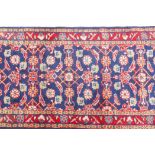 A large blue ground Persian Sarouk runner with all over design and red borders, 33" x 140"