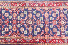 A large blue ground Persian Sarouk runner with all over design and red borders, 33" x 140"