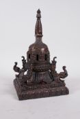 A Tibetan bronze stupa with a gilt patina, decorated with depictions of Buddha and mythical