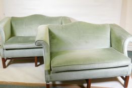 A pair of camel back settees with scroll arms, raised on square moulded supports united by