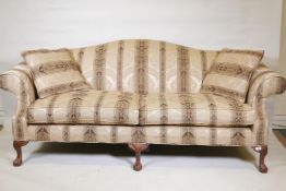 A camel back settee with scroll arms, raised on carved cabriole supports with ball and claw feet,
