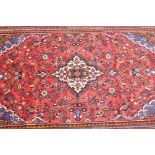 A red ground full pile Persian Sarouk carpet with multicoloured floral design, 82" x 120"