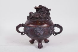 A Chinese bronze censer and cover raised on tripod pawed feet, with two dragon form handles,