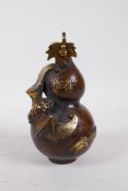 A Chinese filled bronze ornament in the form of a double gourd with a bat, highlighted with gilt,