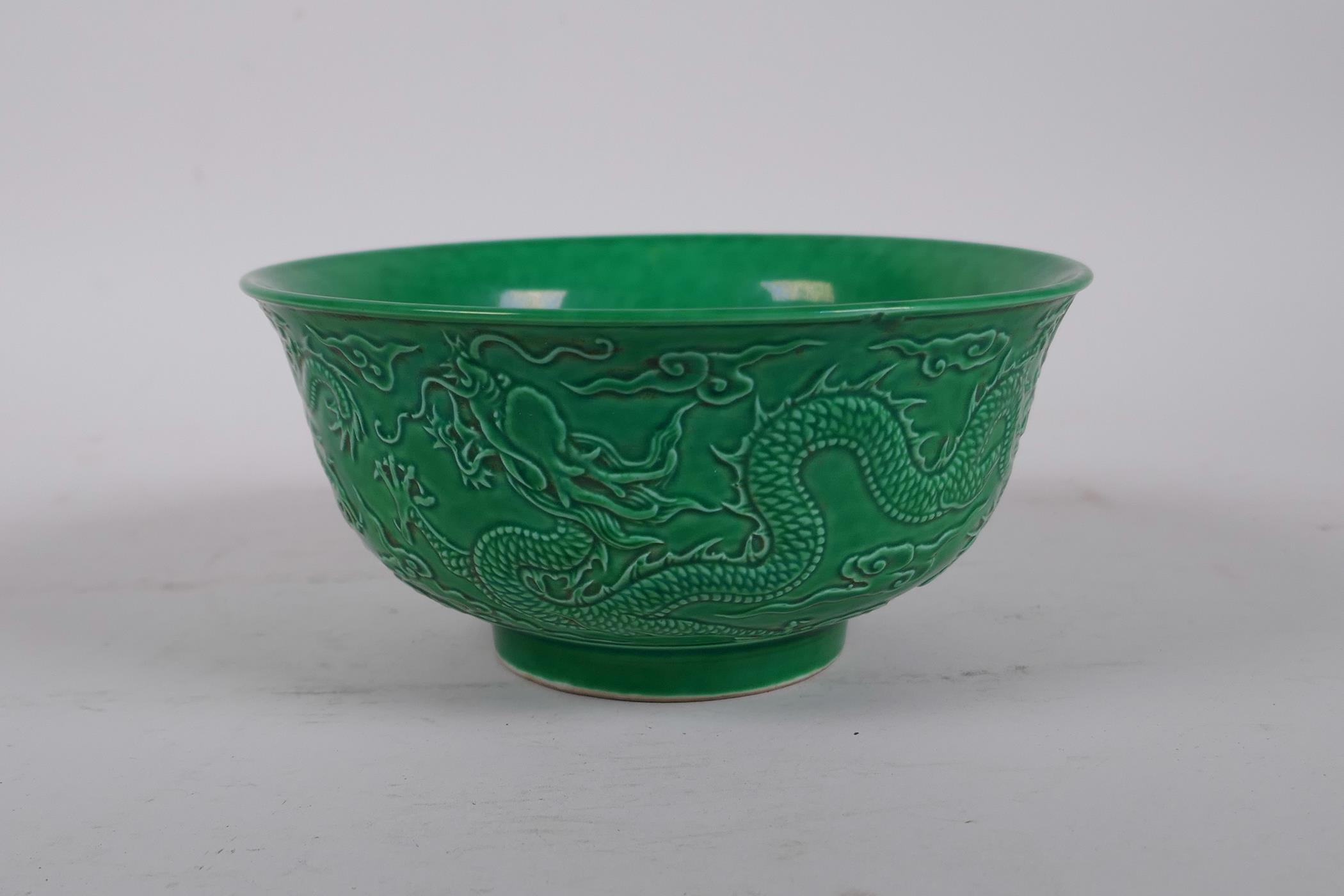 A Chinese green glazed porcelain rice bowl with raised dragon decoration, 6 character mark to