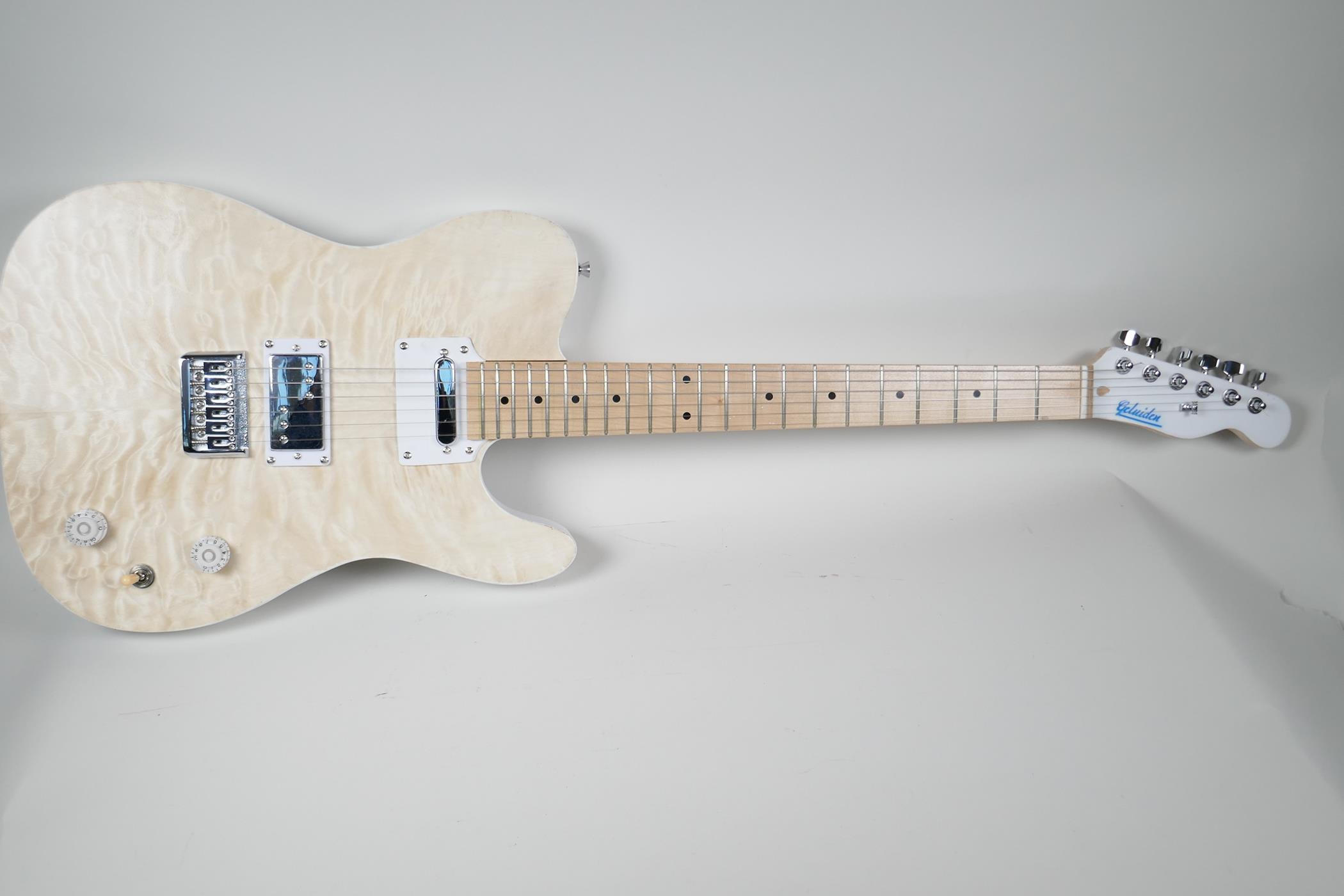 An electric guitar in the style of a Fender with blonde maple veneered body, the head bears label