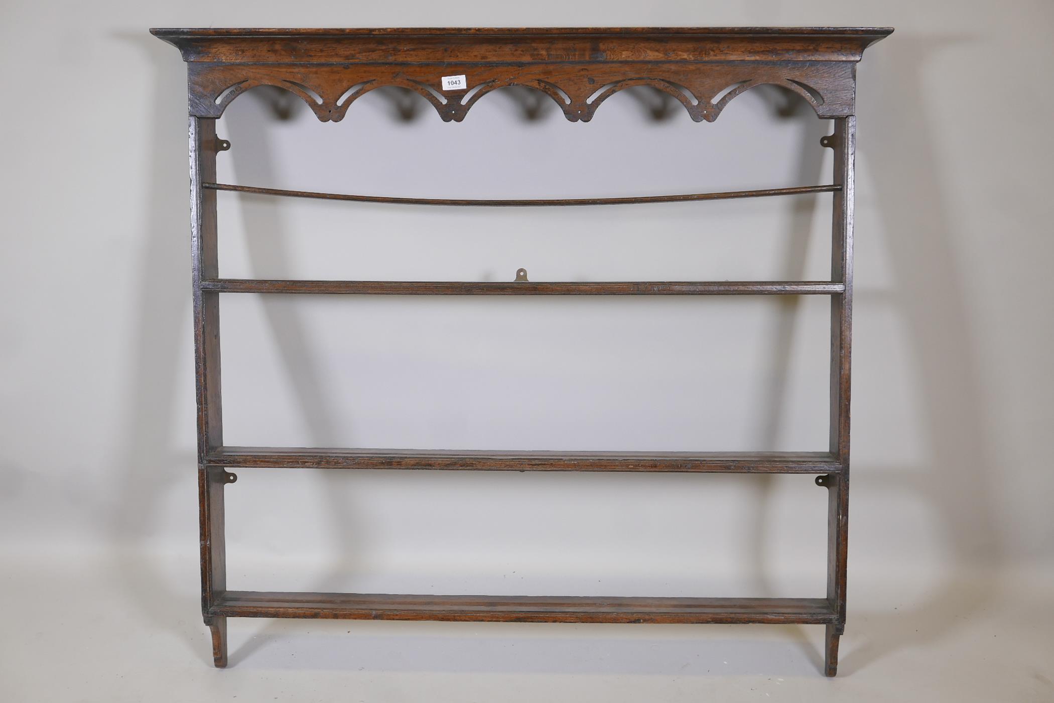 A late C19th/early C20th elm hanging Delft rack, with pierced and shaped frieze and three shelves,