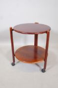 A mid century mahogany two tier occasional table, with folding base, raised on turned supports