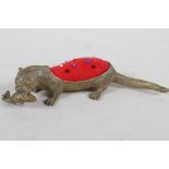 A brass pincushion cast as an otter with fish in its mouth, the otter textured with a hair effect