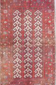 A Middle Eastern full pile red ground wool rug with a three panel geometric design, 34" x 56"