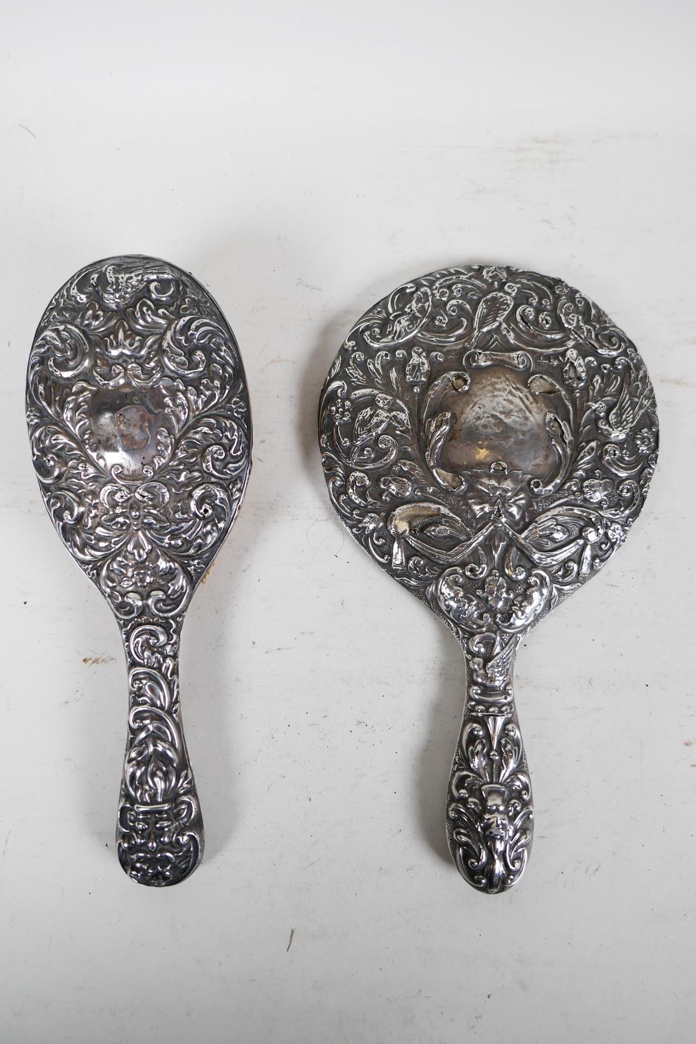 A silver backed late C19th mirror and brush dressing table set, with repousse scrolls, birds and - Image 2 of 7