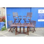 A teak drop leaf garden table, 28½" high, 63" x 37" open, with a set of four folding chairs (5)