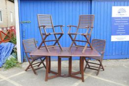 A teak drop leaf garden table, 28½" high, 63" x 37" open, with a set of four folding chairs (5)