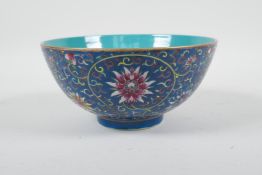 A Chinese polychrome porcelain rice bowl with enamelled scrolling lotus flower decoration on a