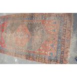 An Eastern tribal woven woolen rug with red ground and central medallion within three borders (