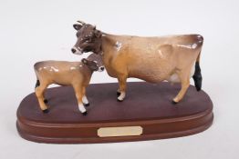 A Beswick figure of a Jersey cow and calf, on a wooden stand, 9½" long, A/F