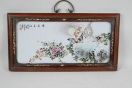 A Chinese polychrome porcelain panel decorated with birds and flowers on a rocky outcrop, in a