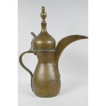 An Islamic brass coffee pot with hinge cover, (signed), 16" high