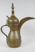 An Islamic brass coffee pot with hinge cover, (signed), 16" high