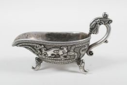 A Chinese white metal libation cup with stylised dragon decoration and tripod feet, mark to base,