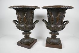 A pair of classical Grand Tour style bronze pedestal urns decorated with many figures on square