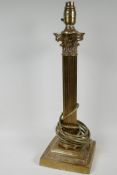 A tall brass table lamp with ribbed column and acanthus capitol on square base