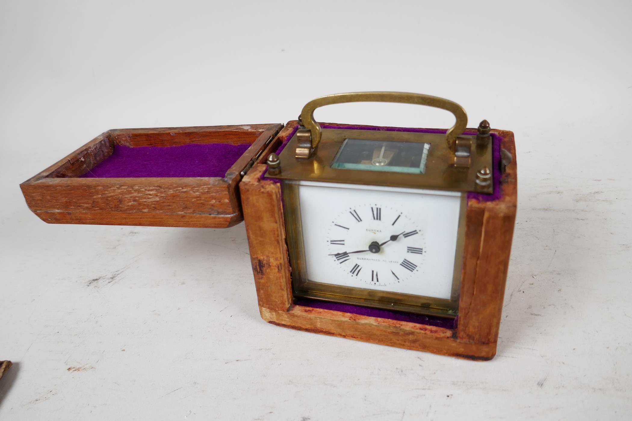 A Eureka brass cased carriage clock in a travel case, the clock with white enamel dial and Roman