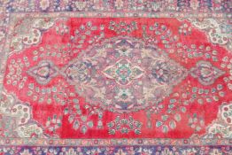 A vintage Iranian carpet from the Tabriz region, with floral medallion design on a red field with