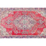 A vintage Iranian carpet from the Tabriz region, with floral medallion design on a red field with